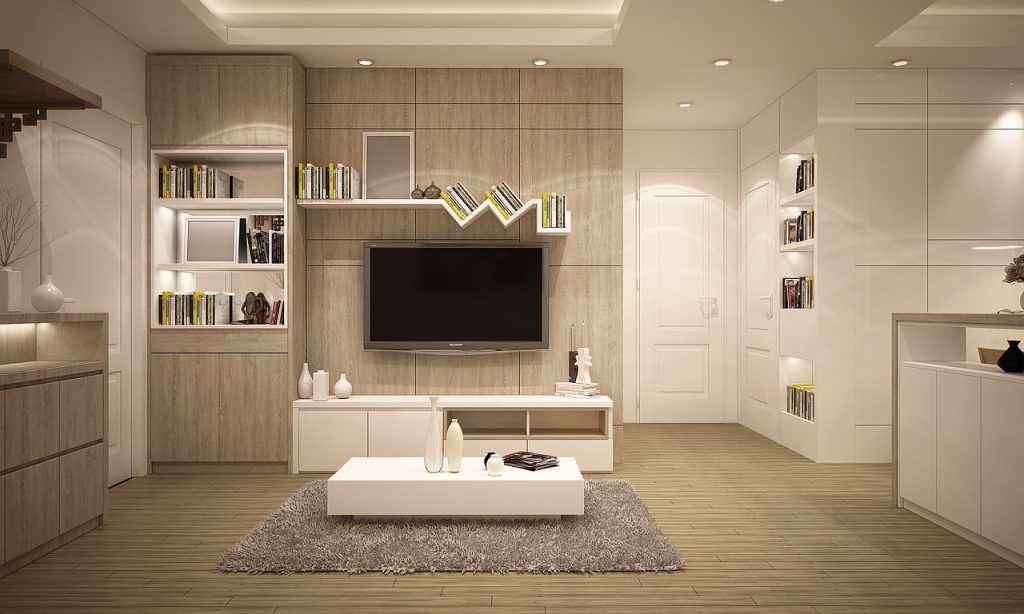 Modern living room with wooden accents, wall-mounted TV, shelves, and white furnishings creating a cosy atmosphere